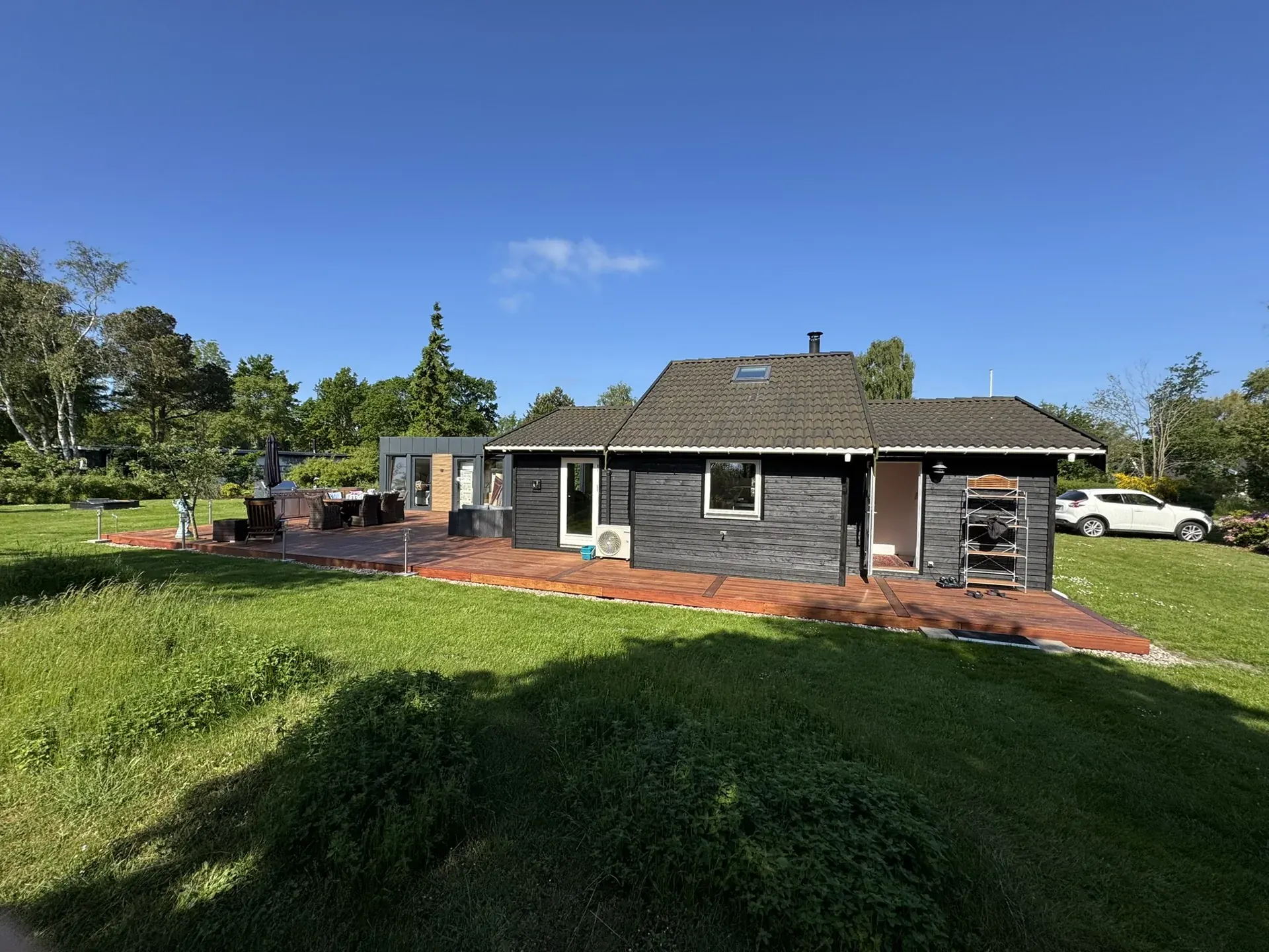 Stor træterrasse langs sort sommerhus