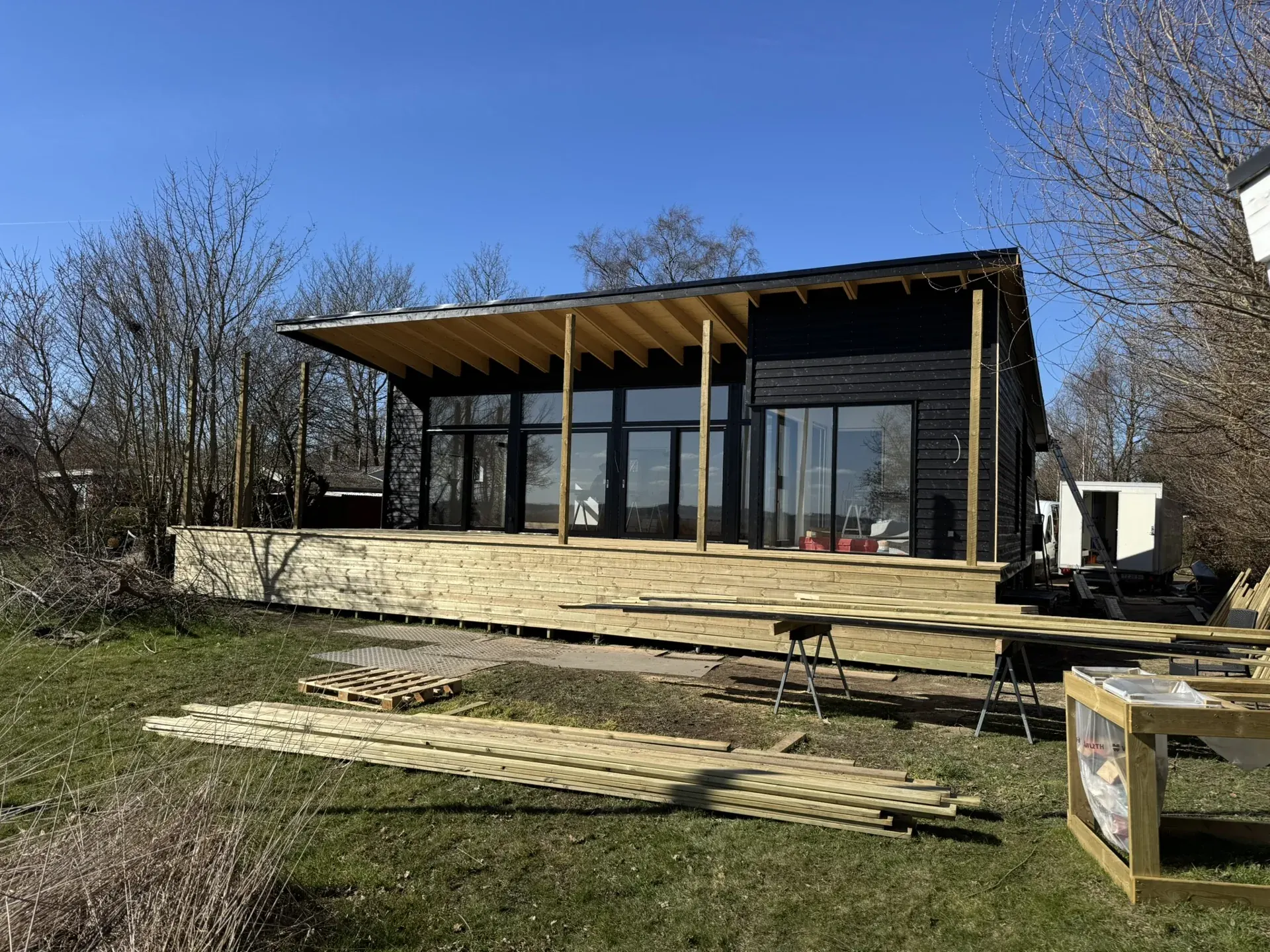Sort træhus med stor glasfacade og terrasse