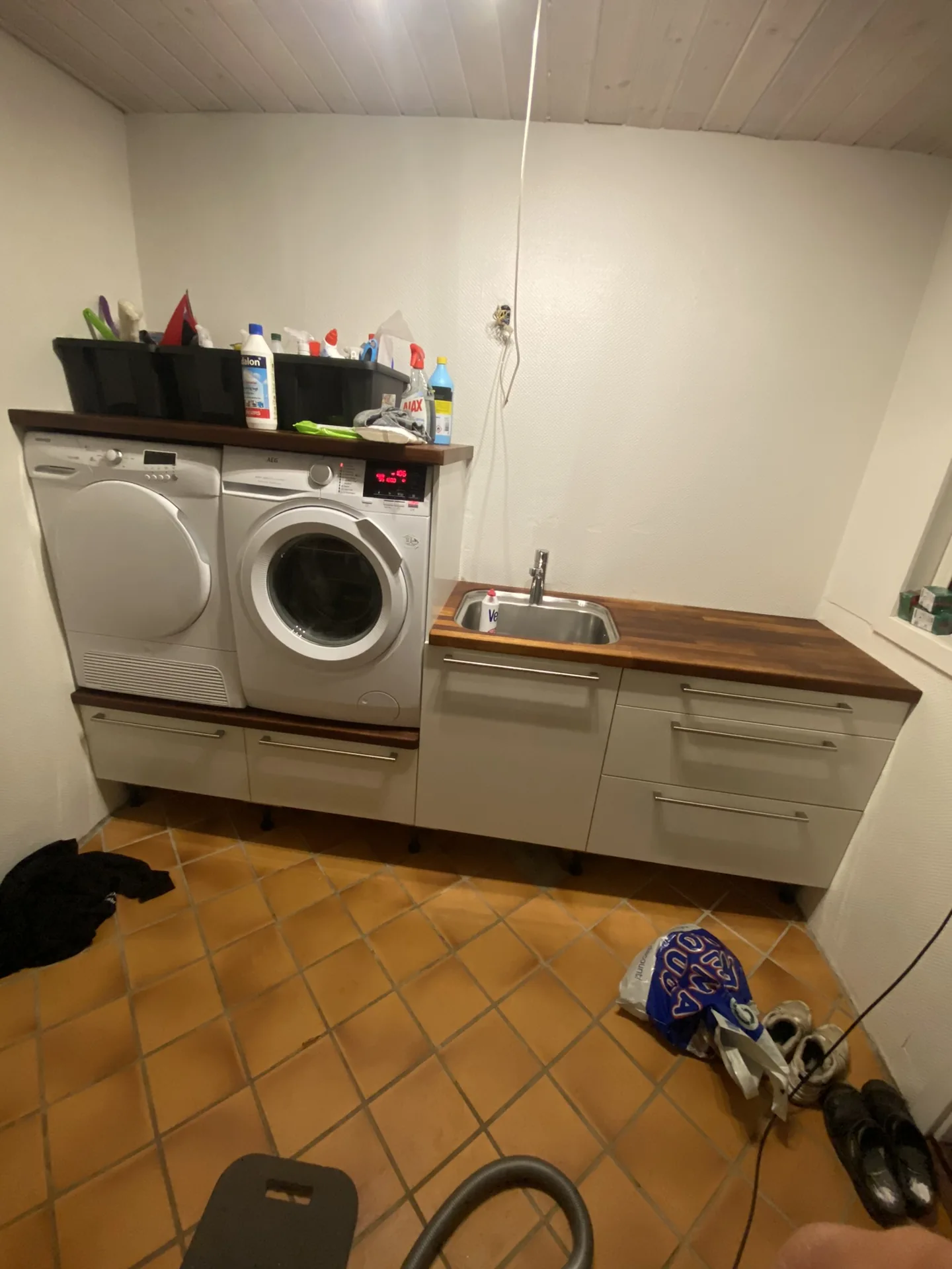 Færdigt bryggers med skabe, bordplade og plads til vaskemaskiner